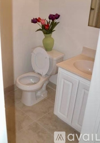 A white toilet with a vase of flowers on top of it.