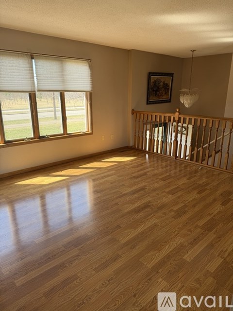 A room with wooden flooring and a window with blinds.