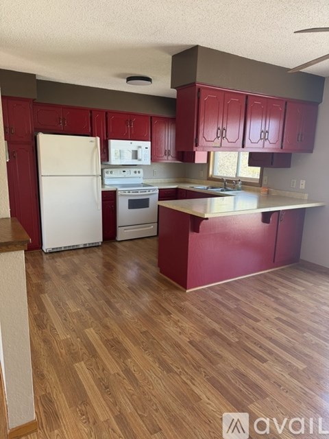 A kitchen with red cabinets and a white fridge.