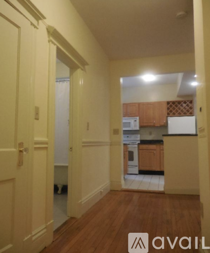A hallway with a kitchen in the background.