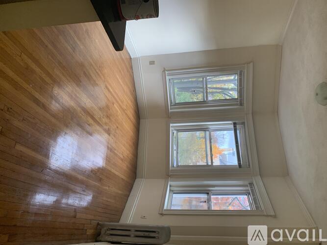 A wooden floor leads to a window with a view of a building.