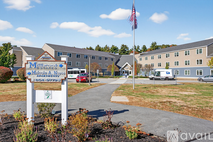 The image shows a sign for Millbrook Apartments with a red vehicle parked in front.