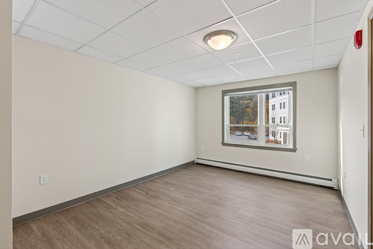 A room with wooden flooring and a window showing a building outside.