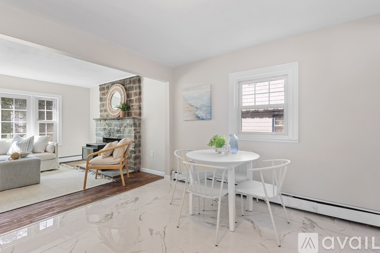 A living room with a fireplace, a chair, a table, and a painting on the wall.