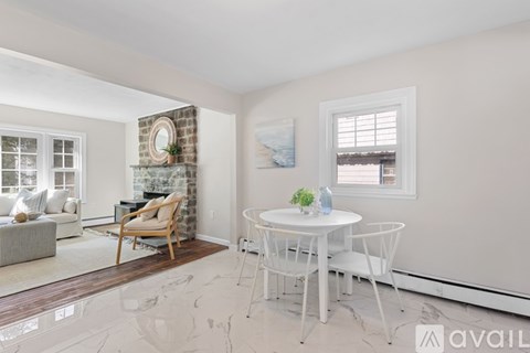 A living room with a fireplace, a chair, a table, and a painting on the wall.