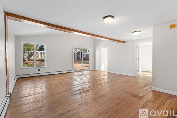 A spacious room with wooden flooring and white walls.