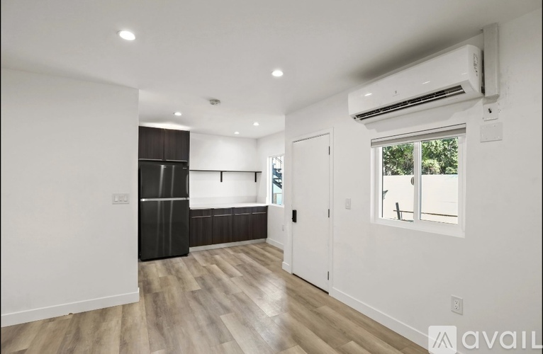 A spacious room with wooden flooring and a large window.