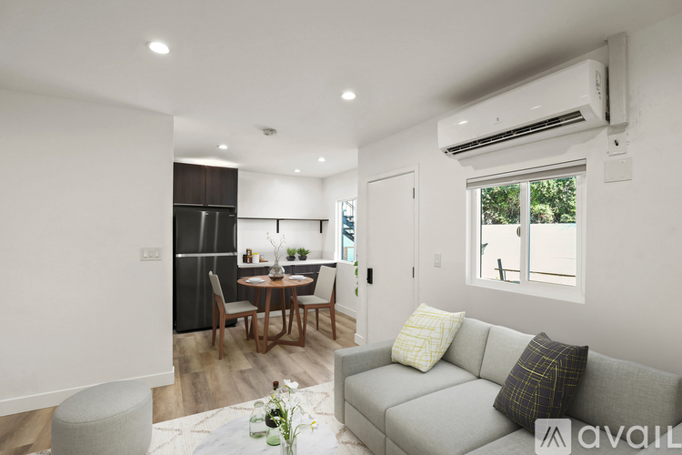 A modern living room with a grey sofa and a dining table with chairs.