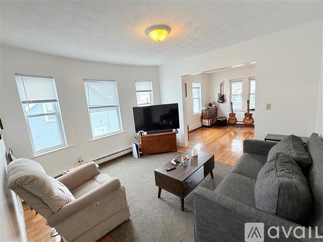 A living room with a grey couch, a chair, a coffee table, and a television.