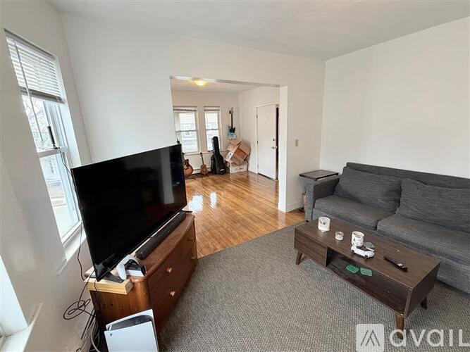 A living room with a grey couch, a wooden coffee table, and a television.