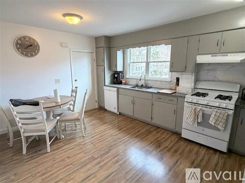 A kitchen with a table and chairs in the foreground and a clock on the wall.