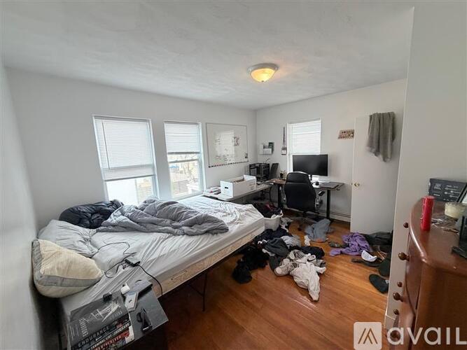 A messy bedroom with a bed, desk, and chair.