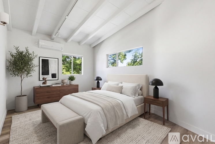 A bedroom with a large bed, a nightstand, and a small tree.