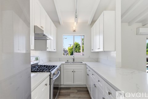 A kitchen with white cabinets and a marble countertop.