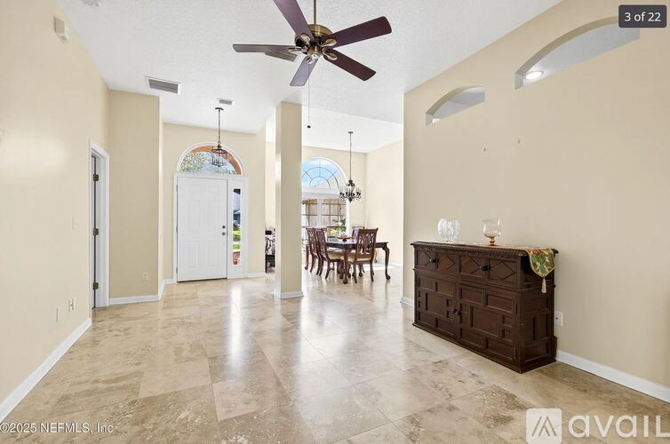 A spacious room with a fan, chairs, and a dresser.