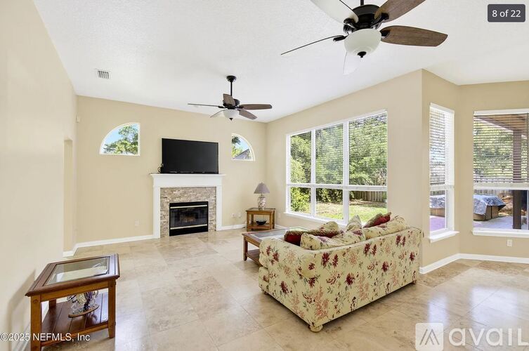 A living room with a couch, a fireplace, and a ceiling fan.