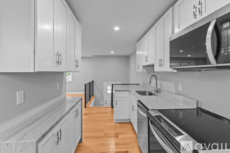 A modern kitchen with white cabinets and a black countertop.