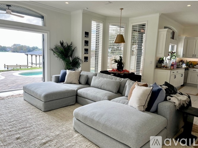 A living room with a grey sofa and a pool in the background.