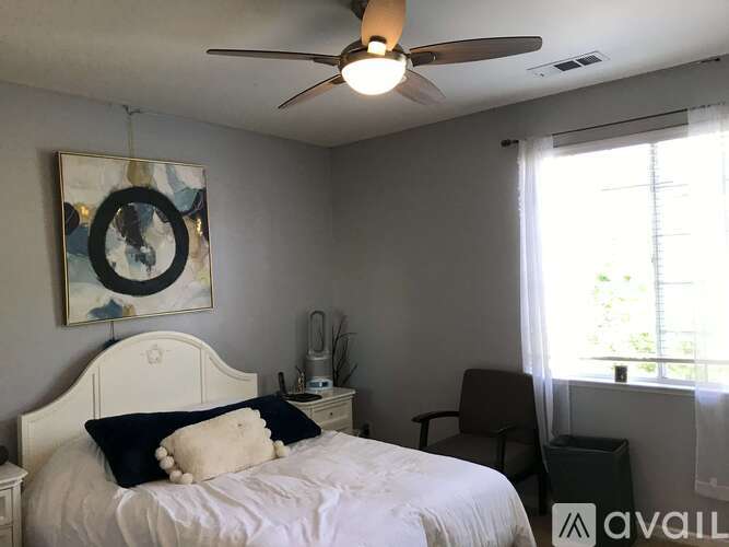 A bedroom with a white bed and a ceiling fan.