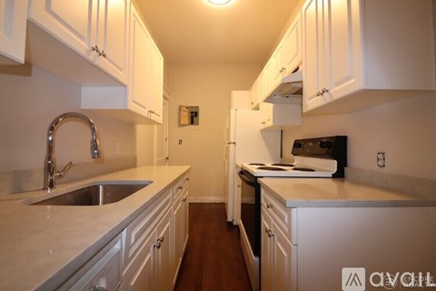 A kitchen with white cabinets and a stainless steel sink.