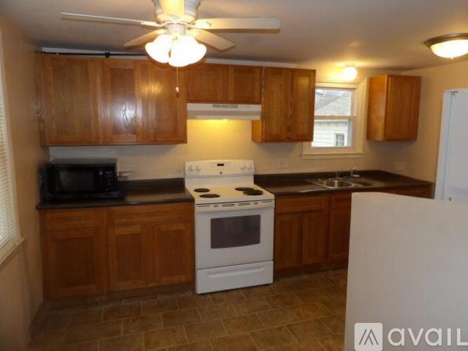 A kitchen with wooden cabinets and a black microwave.