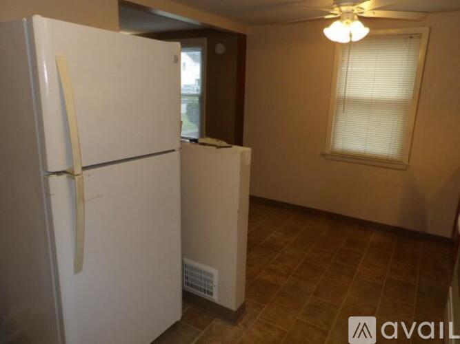 A white refrigerator is in a kitchen with a tile floor.