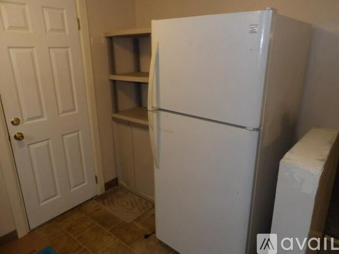 A white refrigerator in a kitchen with a door and a shelf.