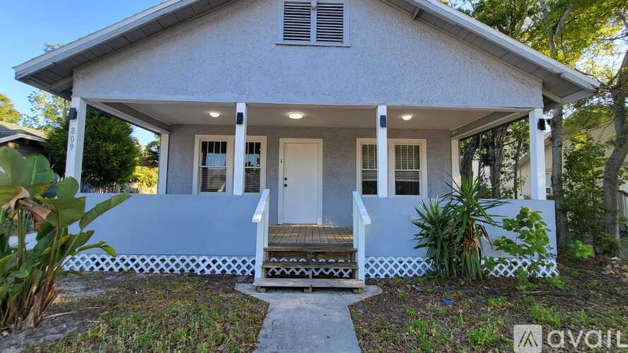 A small white house with a porch and a sign that says "available".