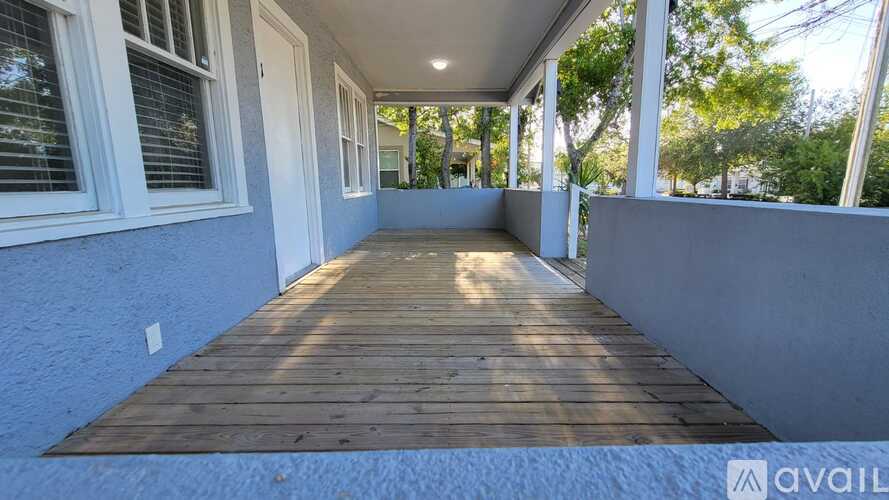 A wooden deck with a white wall and a door.