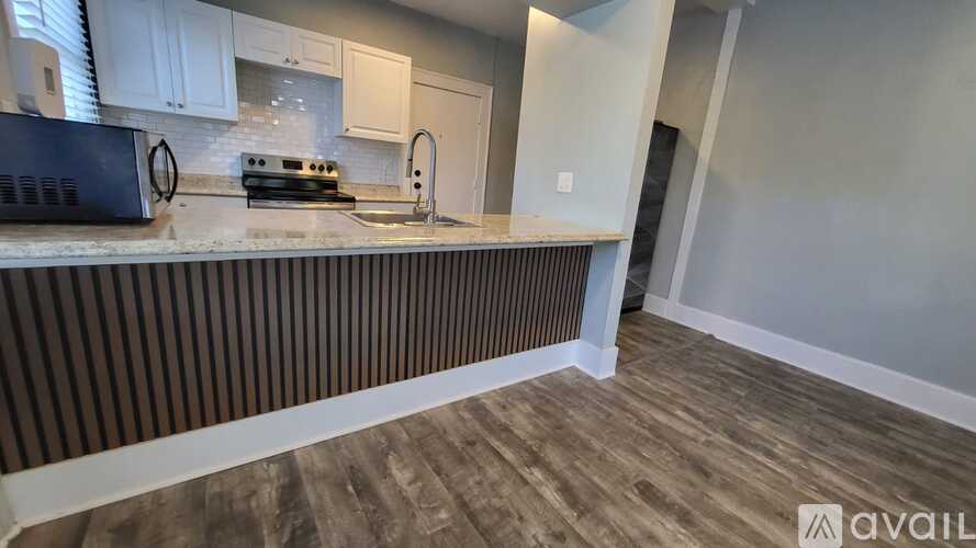 A kitchen with a black microwave, stove, and sink.