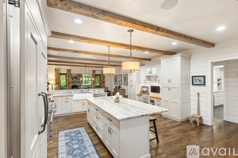 A kitchen with white cabinets and a marble island.