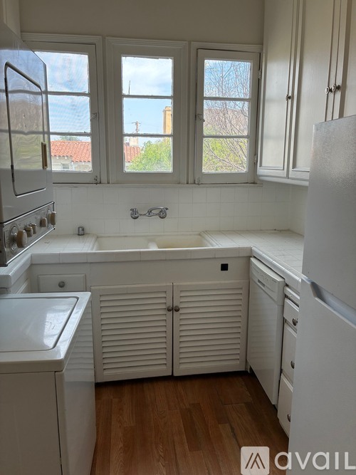 A kitchen with white appliances and wooden floors.