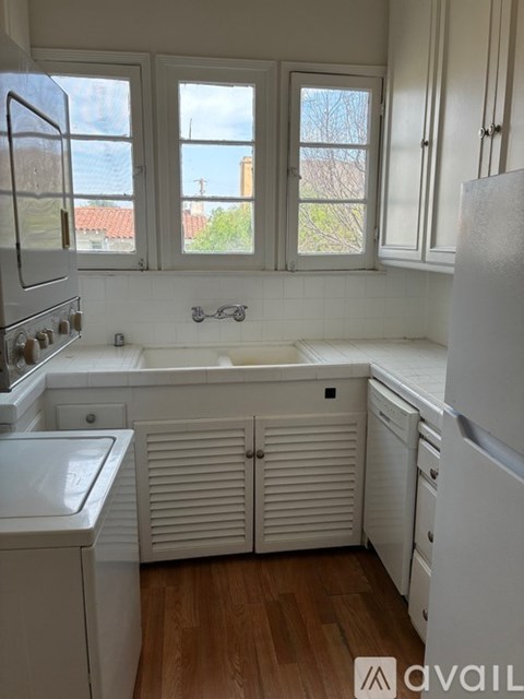 A kitchen with white appliances and wooden floors.
