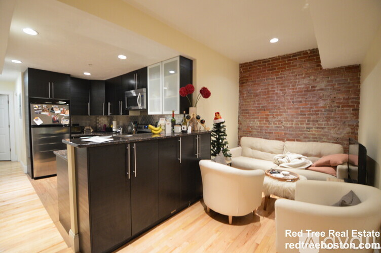A modern kitchen with a brick wall and a living area with a couch and a coffee table.