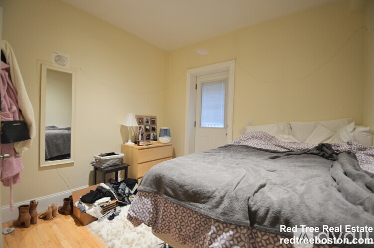 A bedroom with a bed, nightstand, and a mirror.
