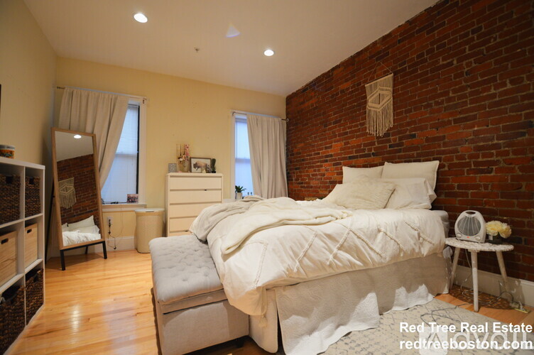 A bedroom with a large bed and a brick wall.