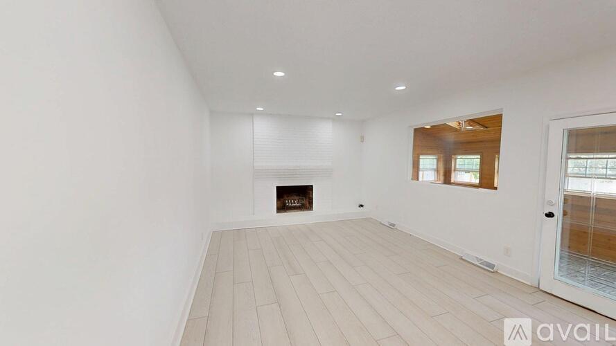 A spacious room with a fireplace and a door leading to another room.