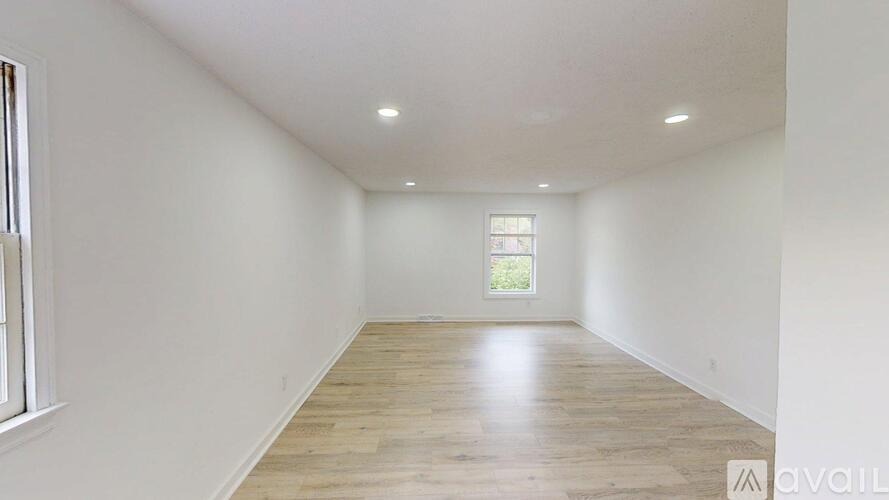 A spacious room with wooden flooring and a window.