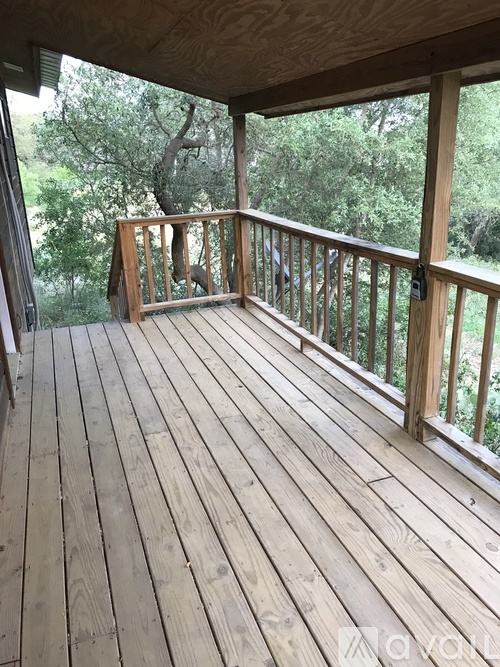 A wooden deck with a railing and a view of trees.