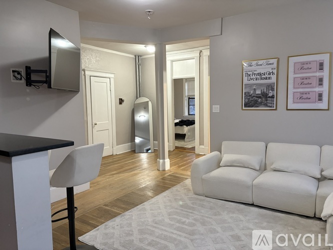 A living room with a white couch and a television on the wall.