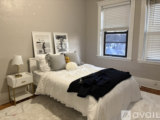 A bedroom with a white bed and a window with blinds.