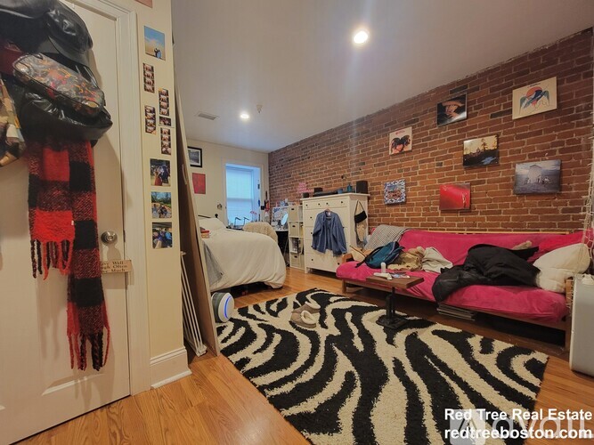 A room with a zebra rug on the floor and a brick wall.