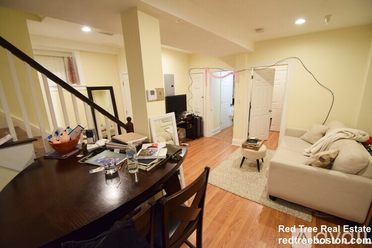 A living room with a couch, a chair, a coffee table, and a dining table.
