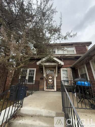 A house with a brown front door and a black railing.