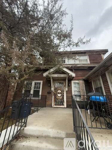 A house with a brown front door and a black railing.