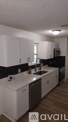 A kitchen with white cabinets and black countertops.
