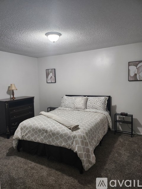A bedroom with a bed, nightstand, and lamp.