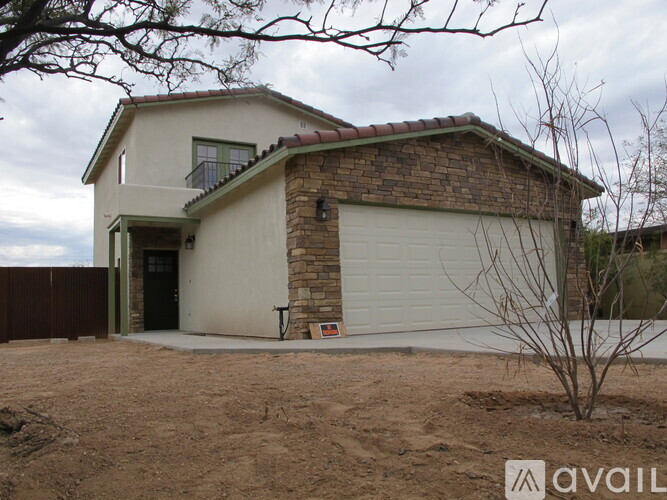 A house with a garage and a tree in front of it.