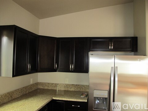 A kitchen with black cabinets and a stainless steel refrigerator.