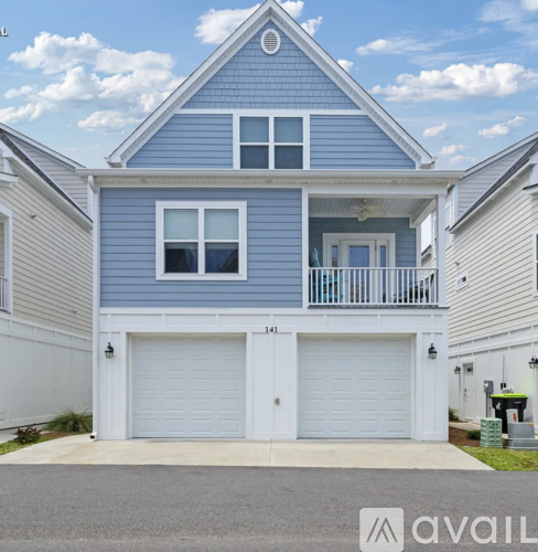 A blue house with two garage doors and a balcony.